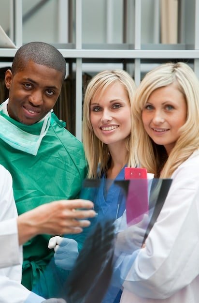 A group of professionals in healthcare settings smiling confidently, representing the types of employment that could qualify for PSLF. The image is bright and conveys professionalism.